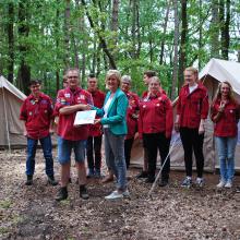 Overhandiging van de "cheque" met de tenten op de achtergrond